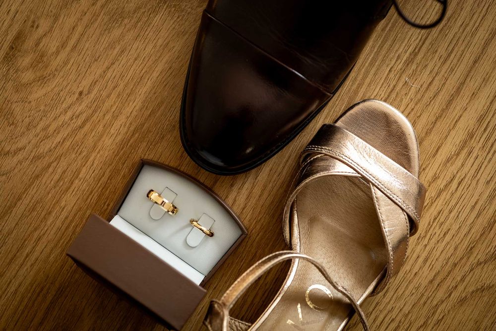 Wedding rings and jewelry details arranged on a rustic wooden surface.