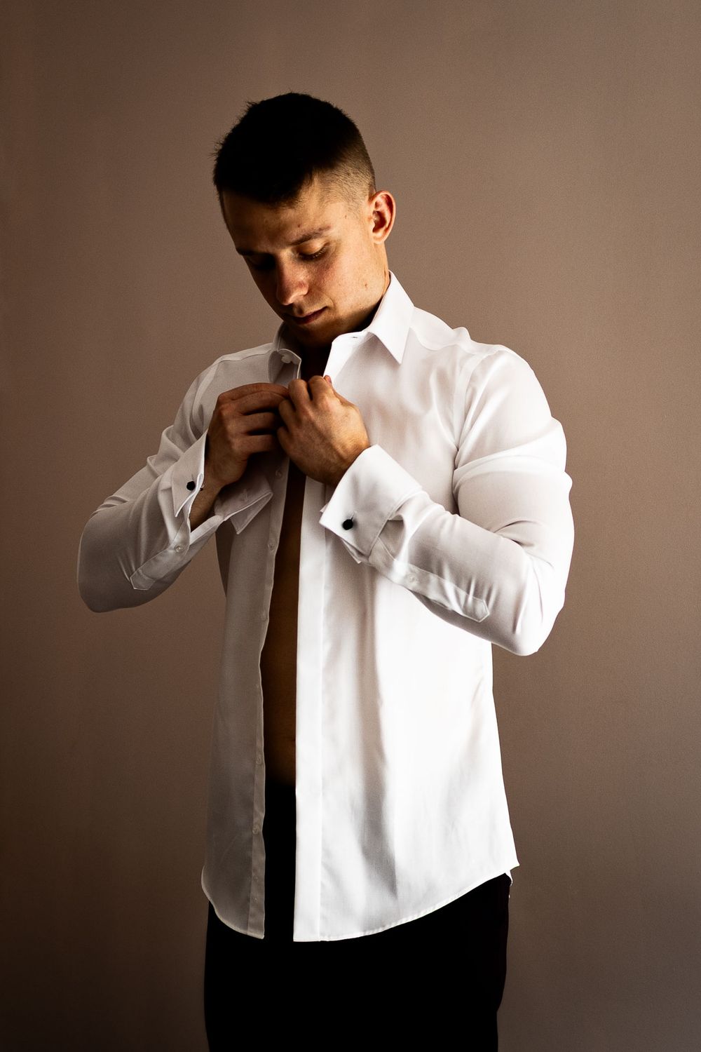 Person in white dress shirt and black tie against neutral backdrop.