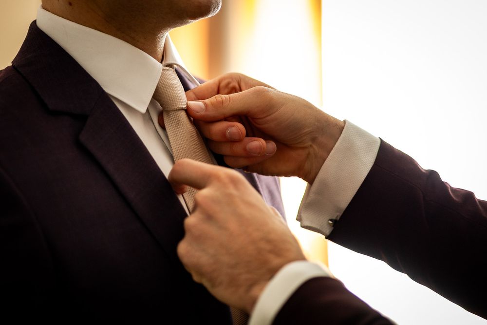 Hands adjusting formal attire in warm lighting.