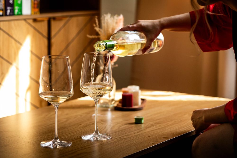 Glasses and bottles on wooden table in atmospheric lighting.