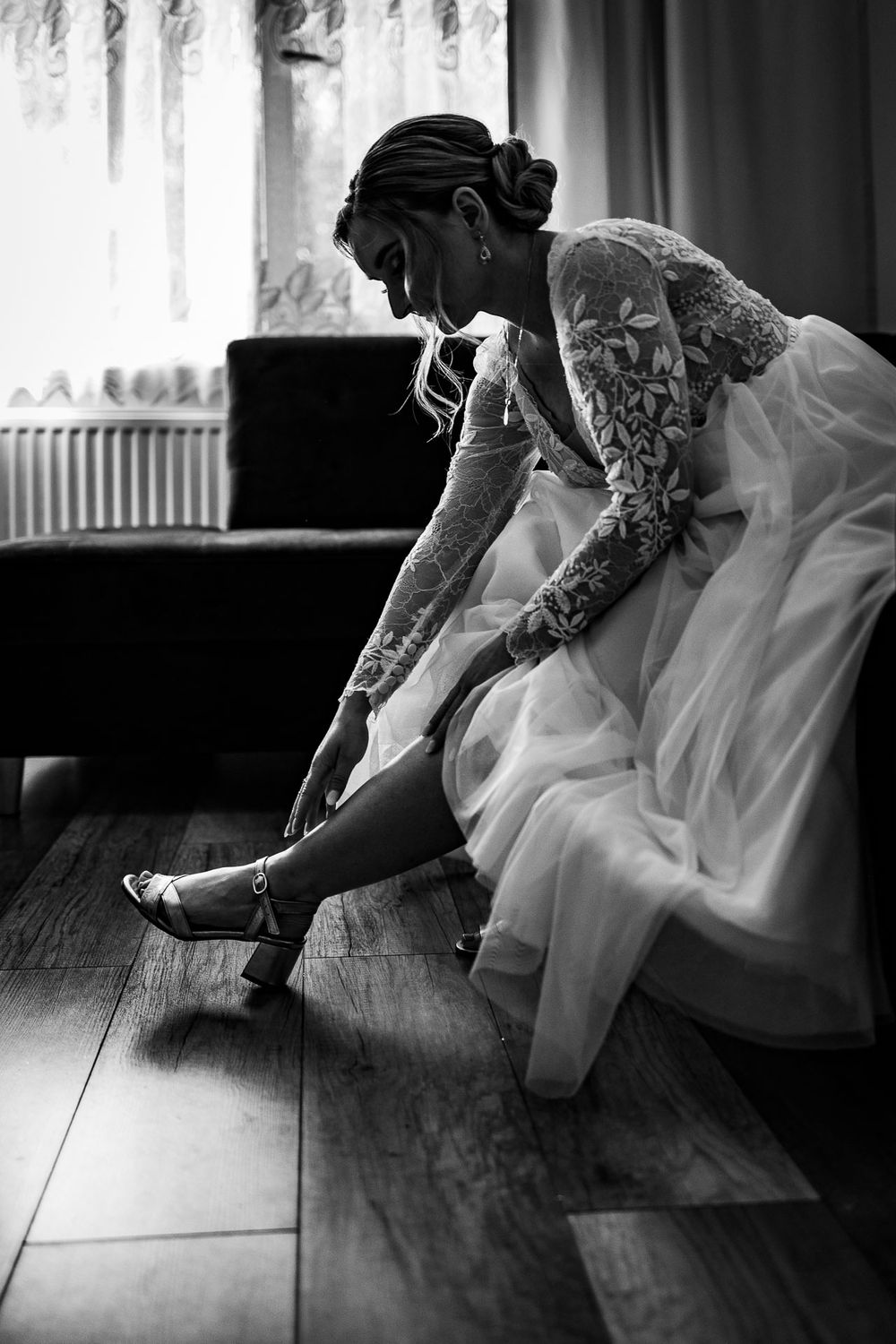 Black and white image of person in wedding dress sitting on floor.