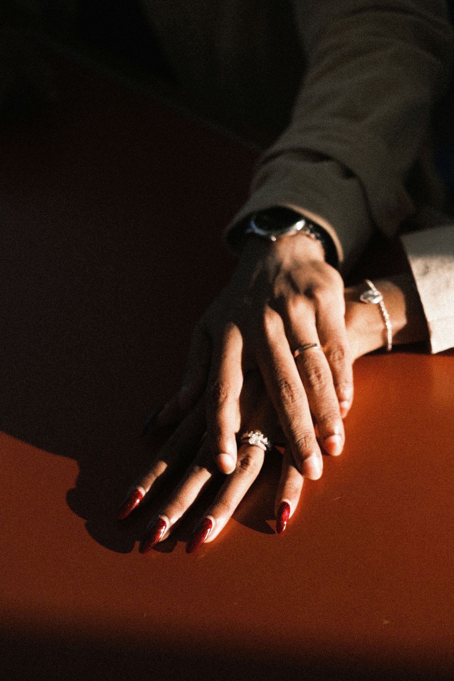 A sequence of close-up shots showing hands with rings casting dramatic shadows on a reddish-brown surface.