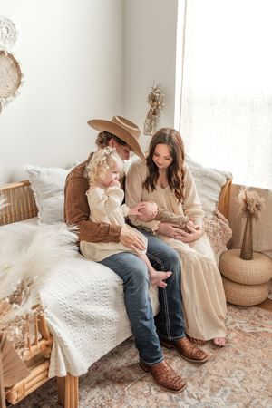 Cozy family moment on white bed with boho decor and natural lighting.