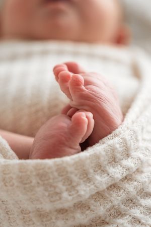 Close-up view of tiny baby feet resting on delicate white lace fabric.
