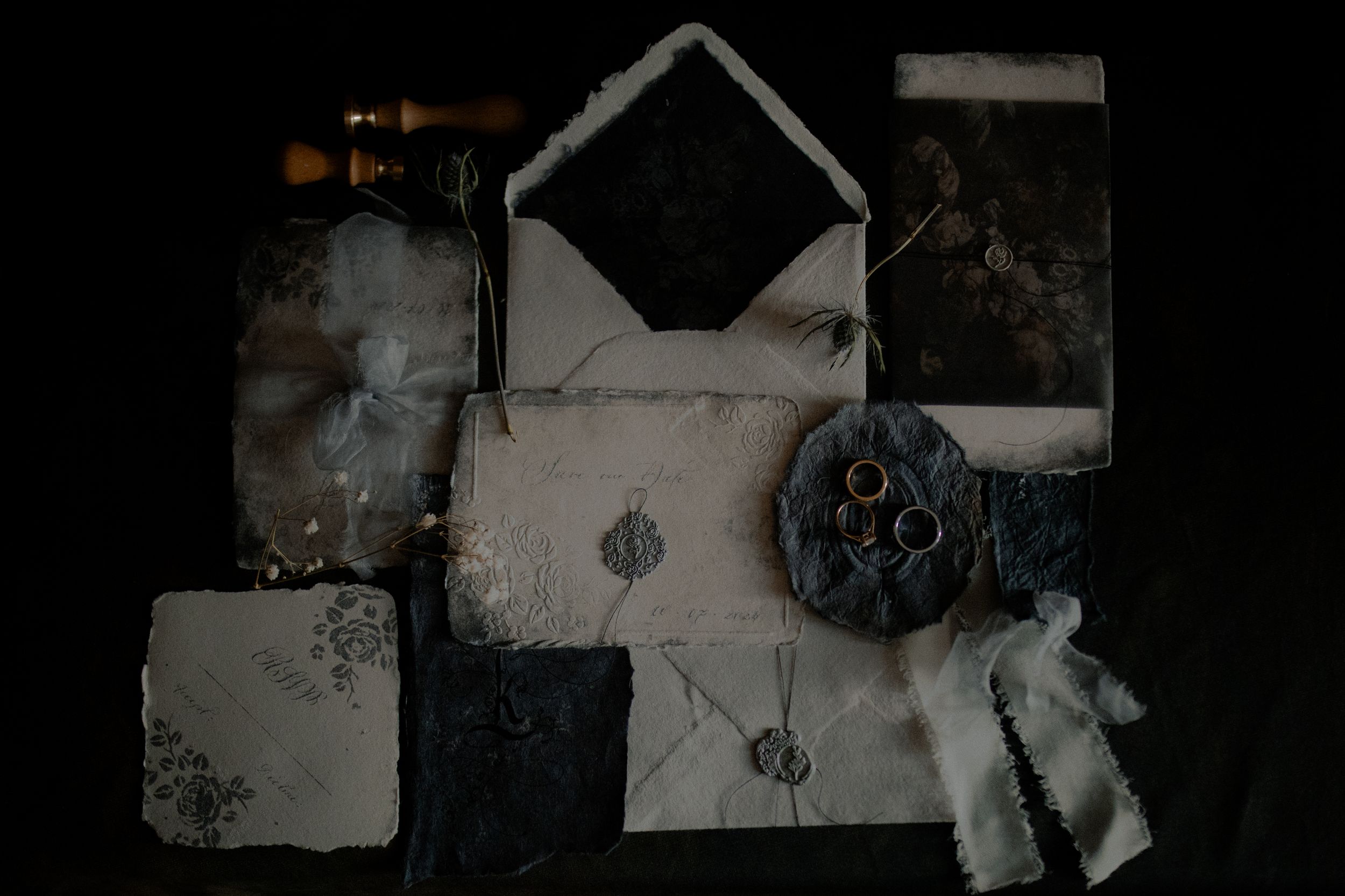 Moody flat lay composition with black and white vintage elements including envelopes and film reel on dark background.
