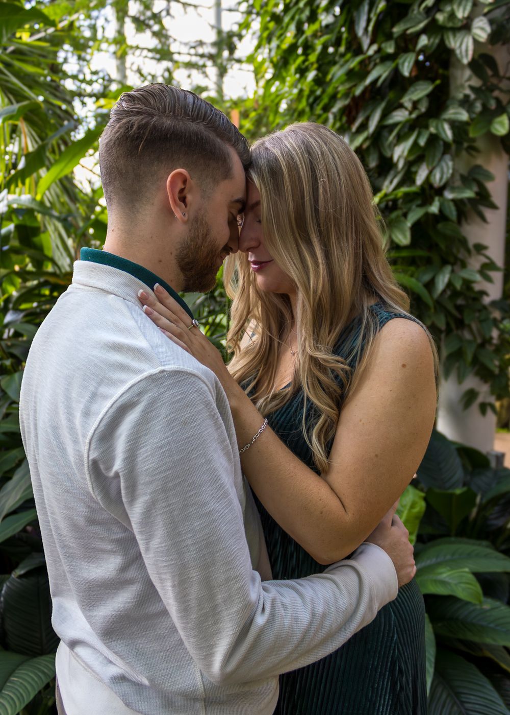 Romantic embraces captured against a backdrop of lush green foliage.
