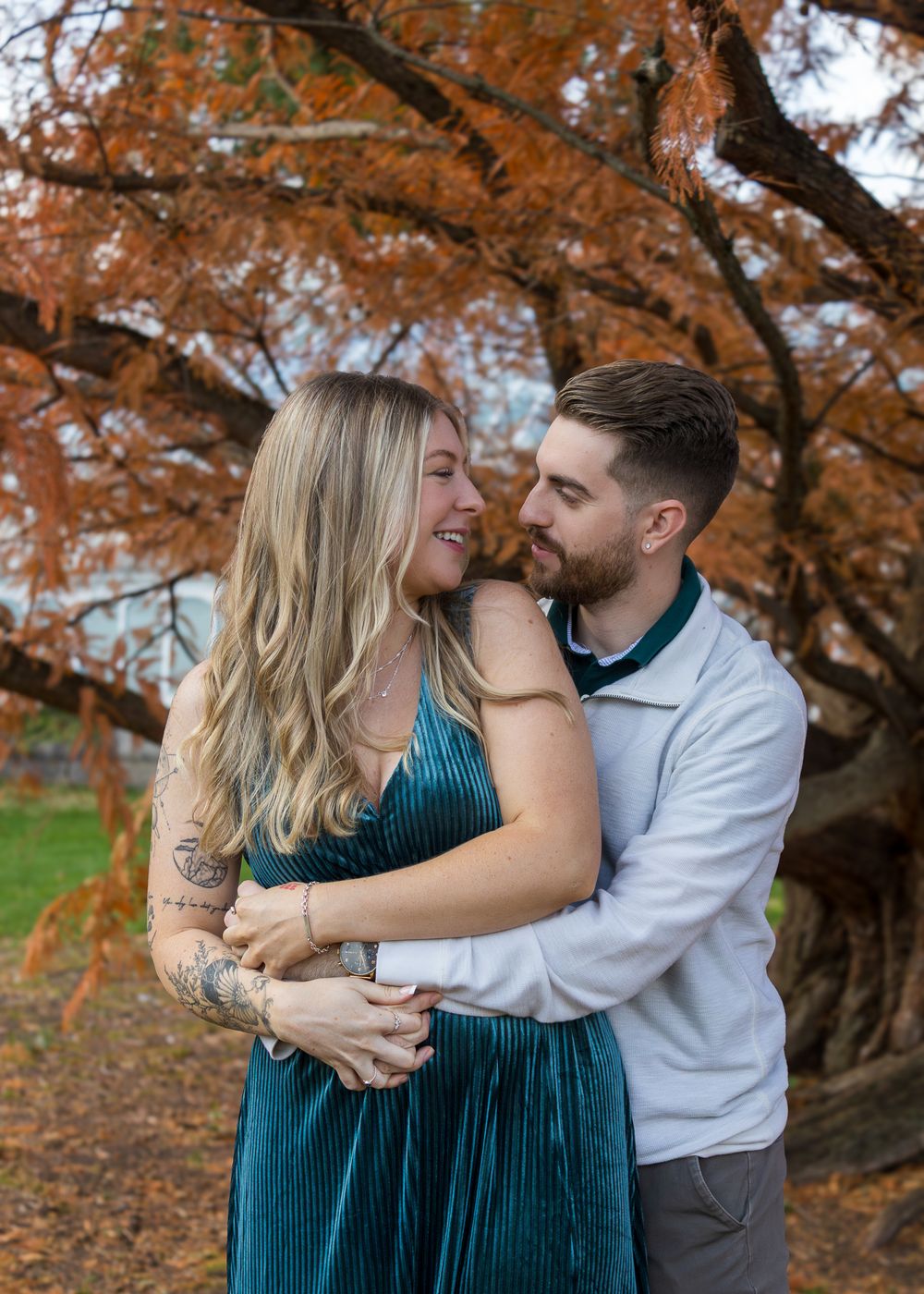 A romantic couple embraces under autumn trees with orange foliage in a series of intimate poses.