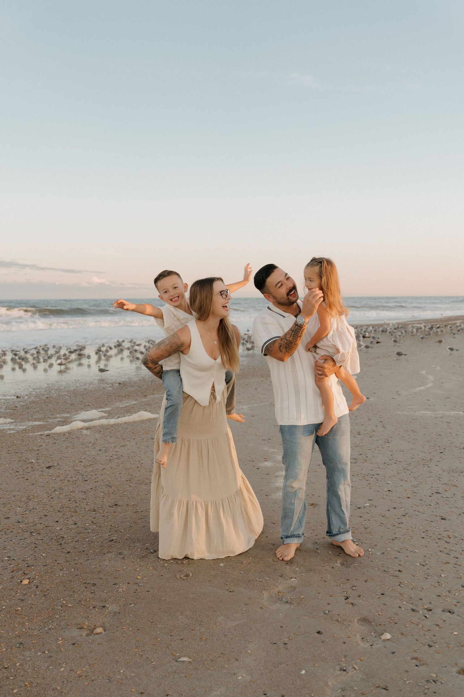 Family enjoying a playful moment together on a sandy beach at sunset.
