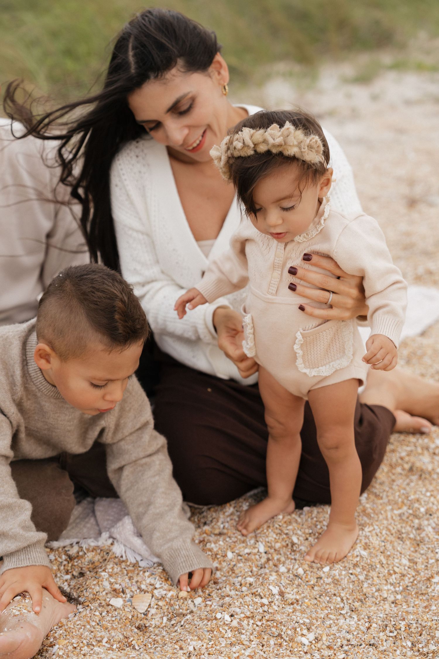 Intimate family photos taken on a pebbly beach showing playful interactions and cuddles.