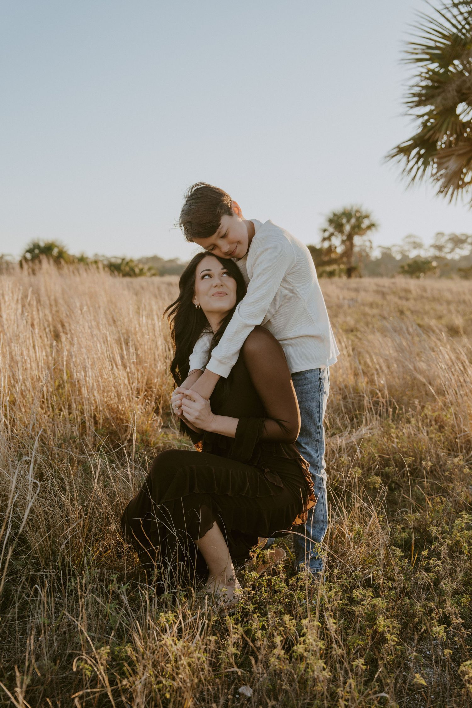 Romantic couple shares intimate moments in a sun-drenched field of tall grass at sunset.