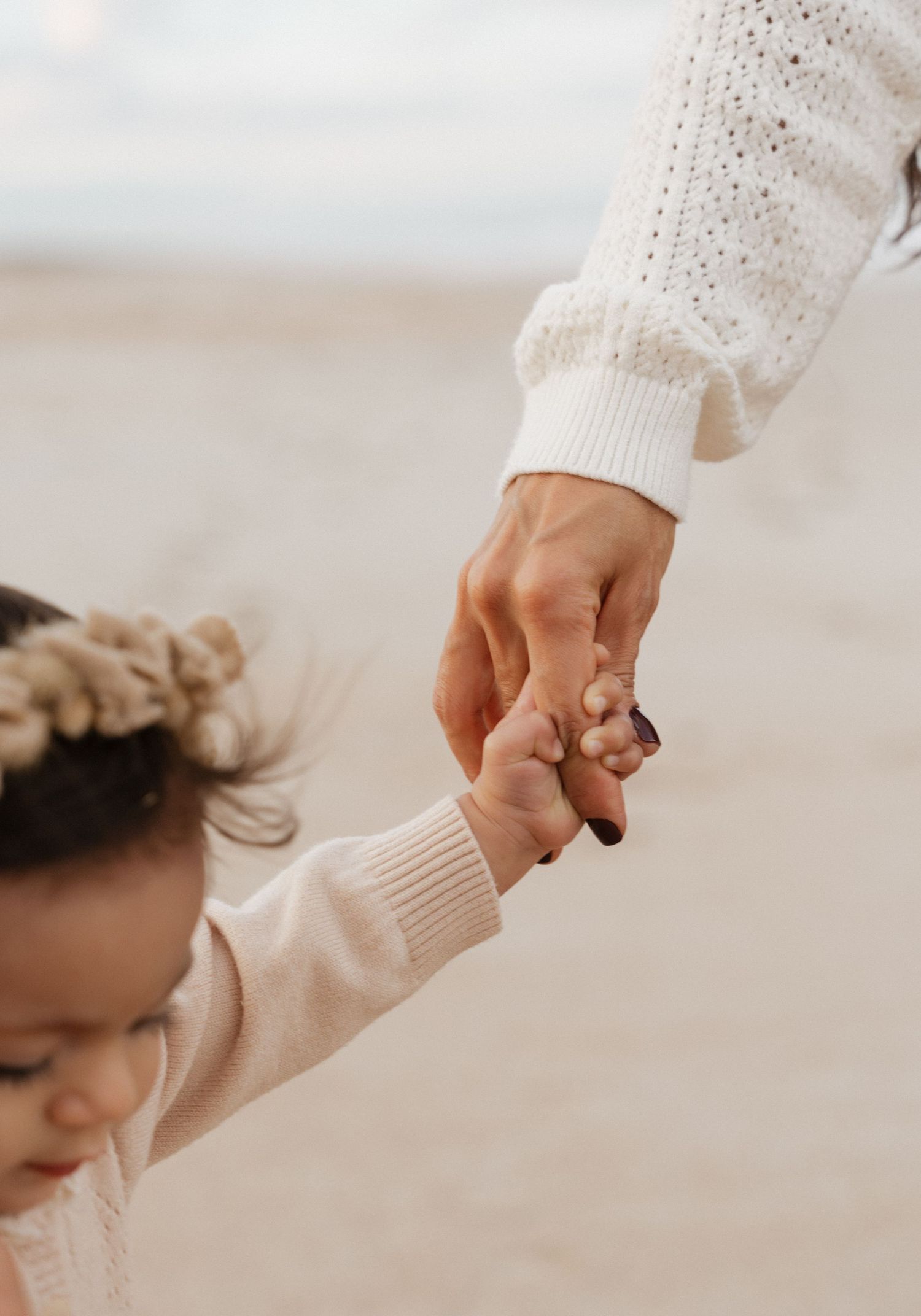 Two hands holding each other gently against a light background in a tender moment of connection.
