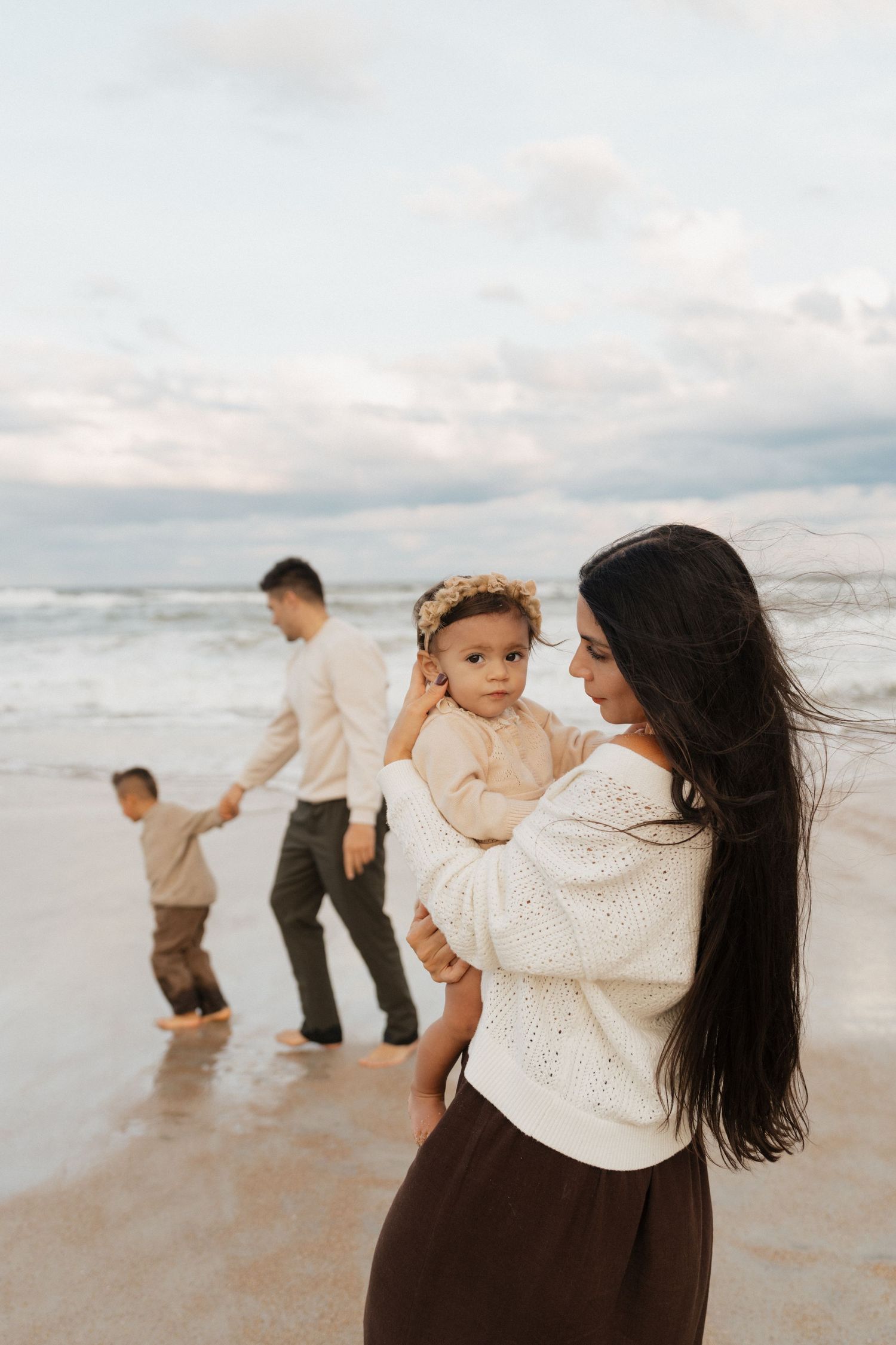 A joyful family moment captured on a cloudy beach with waves in the background.
