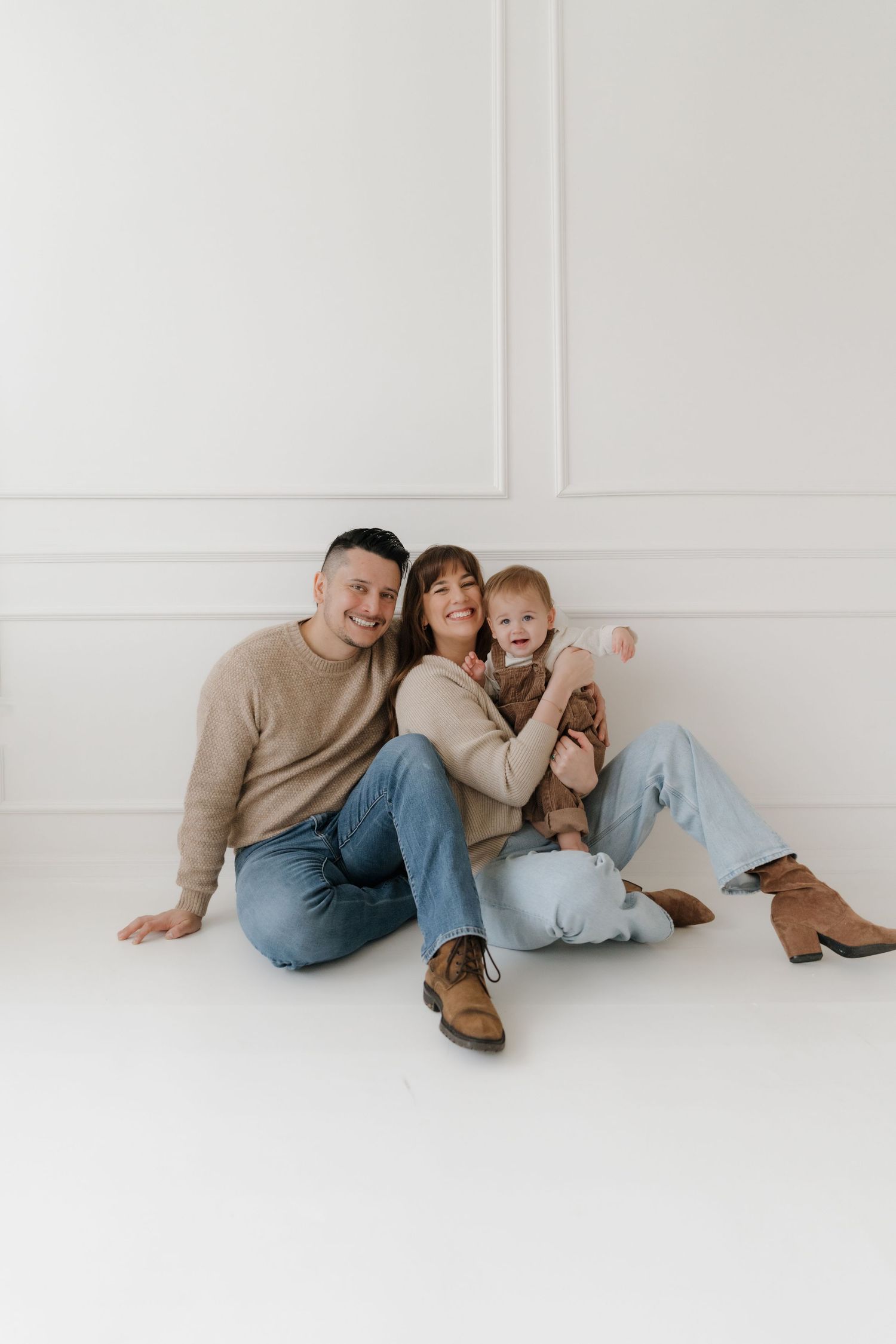 Candid family portrait session on white background showing playful interactions and laughter.