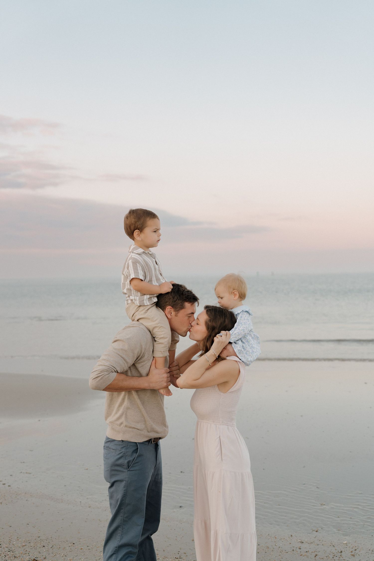 Sweet family portrait session at the beach during golden hour with gentle embraces.