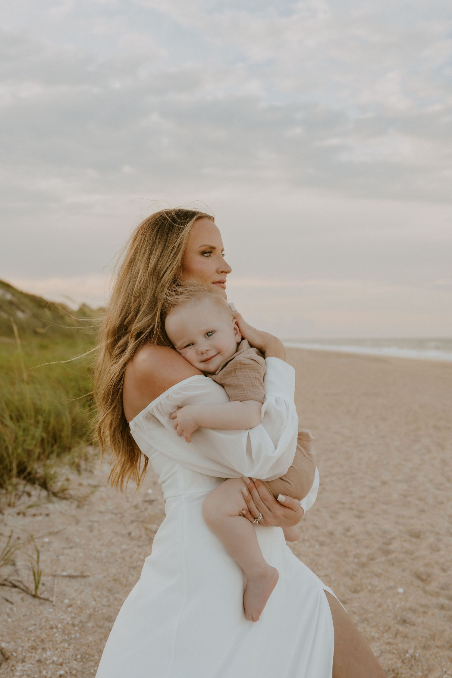 A tender moment between parent and child embracing on a peaceful beach at sunset.