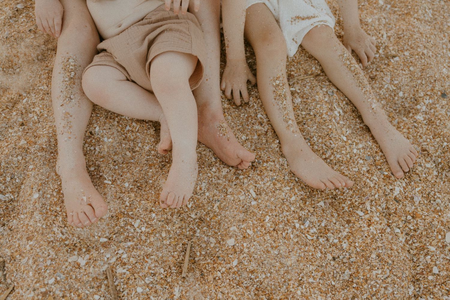 Bare baby feet playing in soft brown sand at the beach, creating a warm and playful summer scene.