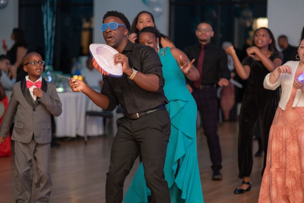 People dancing and celebrating at a formal event with guests wearing elegant attire including a teal dress and dark suit.
