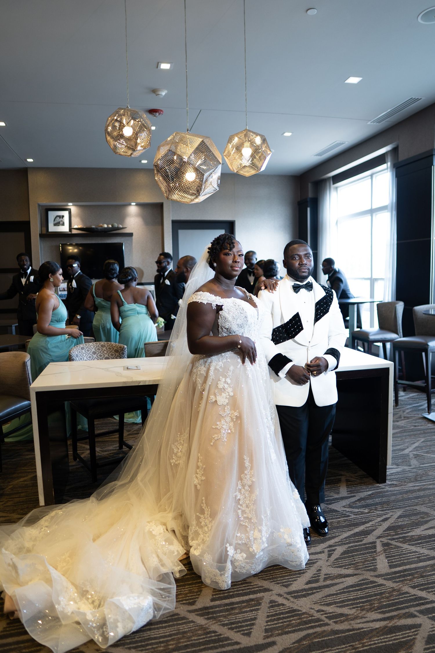 Wedding party gathers in an elegant indoor venue with modern lighting and geometric carpet patterns.