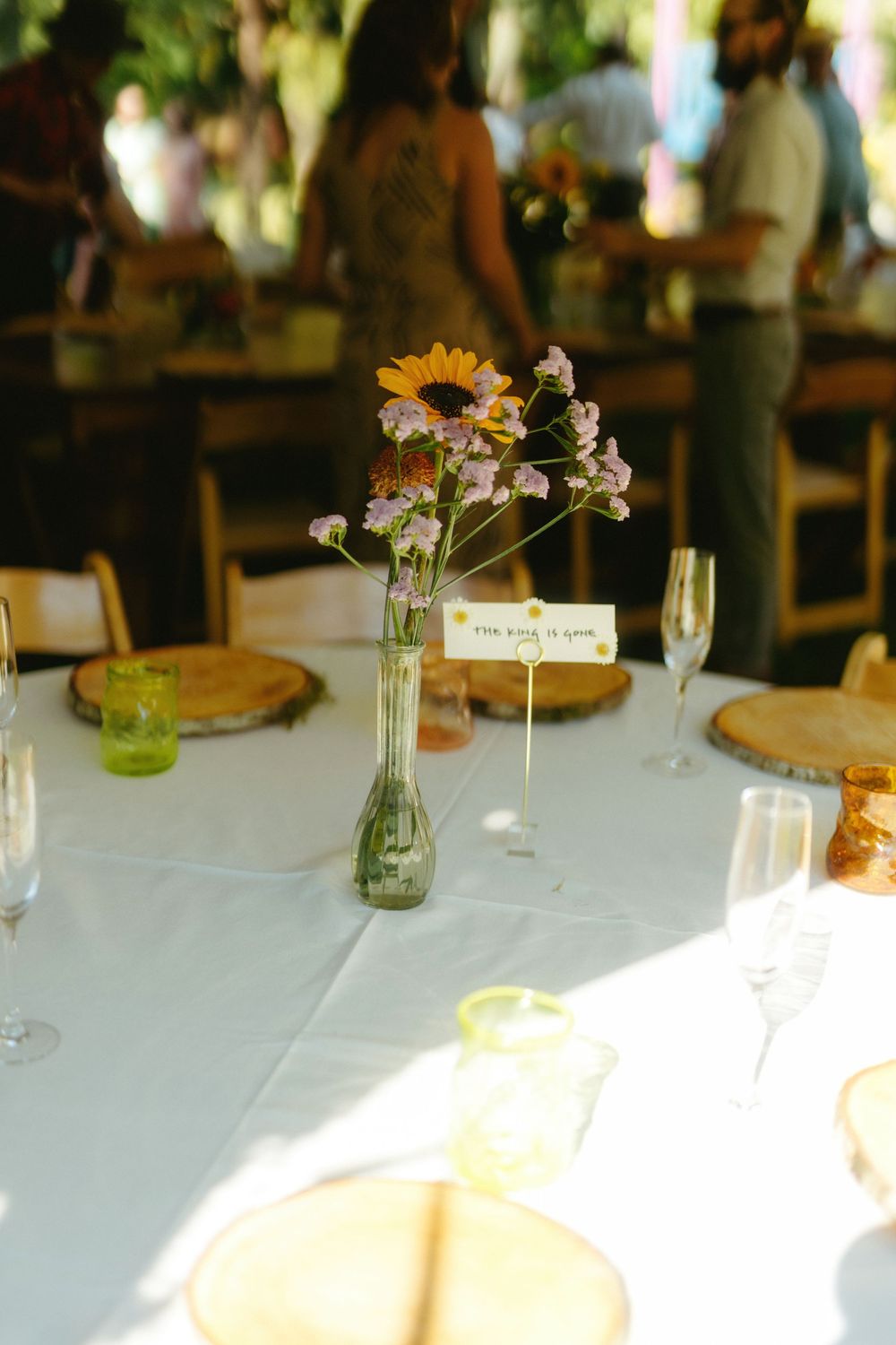 Simple table setting with wildflowers in glass vase and wooden place settings.