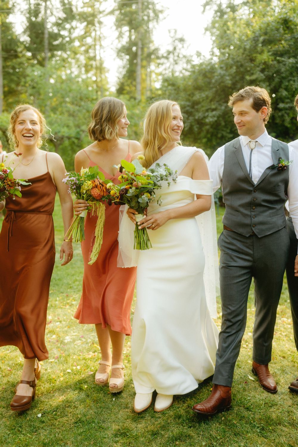 Wedding party shows off their footwear while sitting together outdoors.