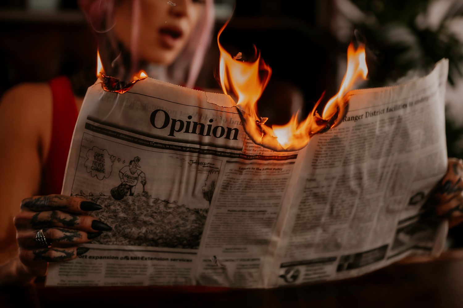 Burning newspaper creating dramatic flames against dark background.