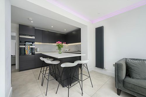 Modern minimalist apartment interior with grey decor, LED lighting, and sleek black and white furniture.