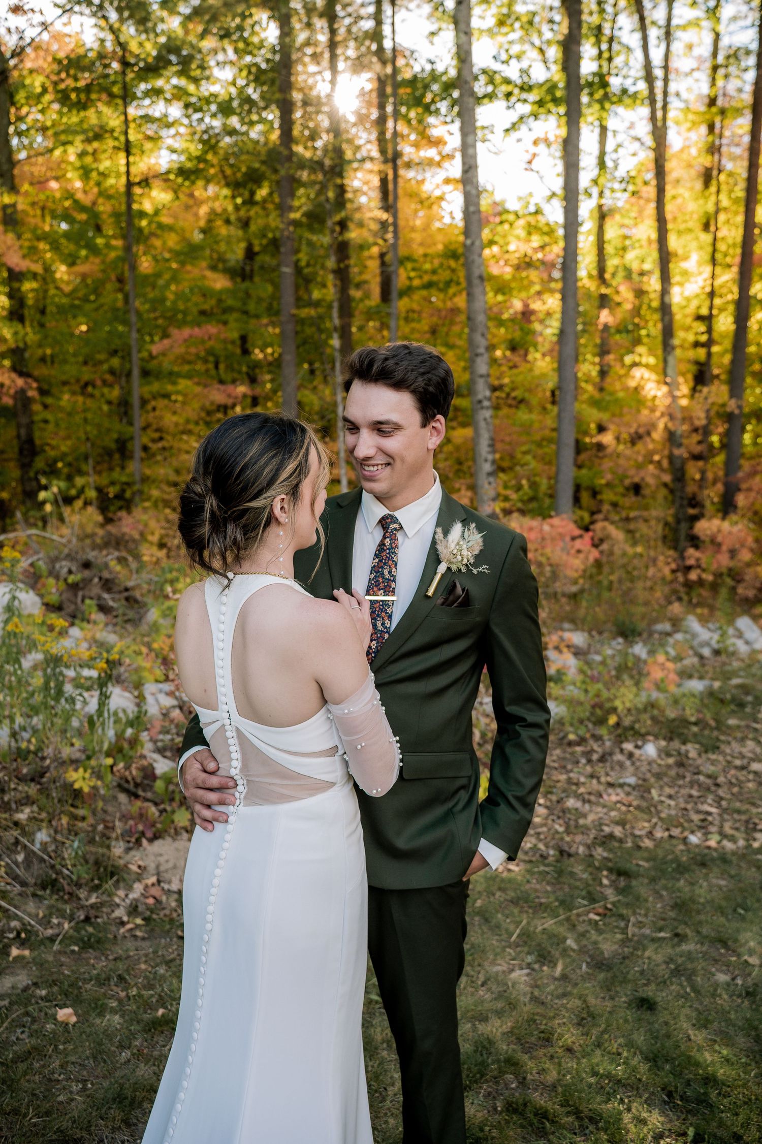 A romantic autumn wedding photo showing a couple embracing in a forest with golden fall foliage in the background.