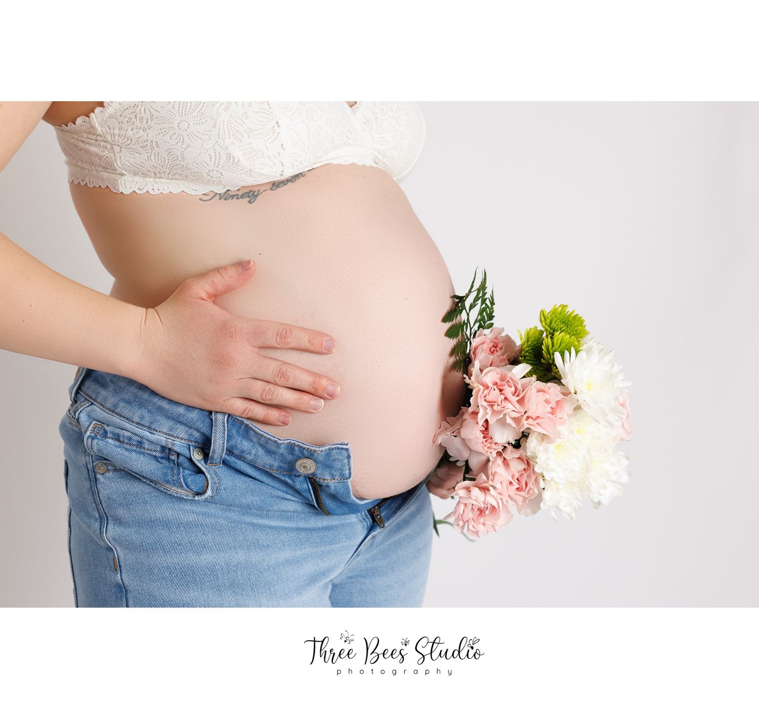 Maternity photo series showing pregnant woman in blue jeans and white top with pink flowers against light background.
