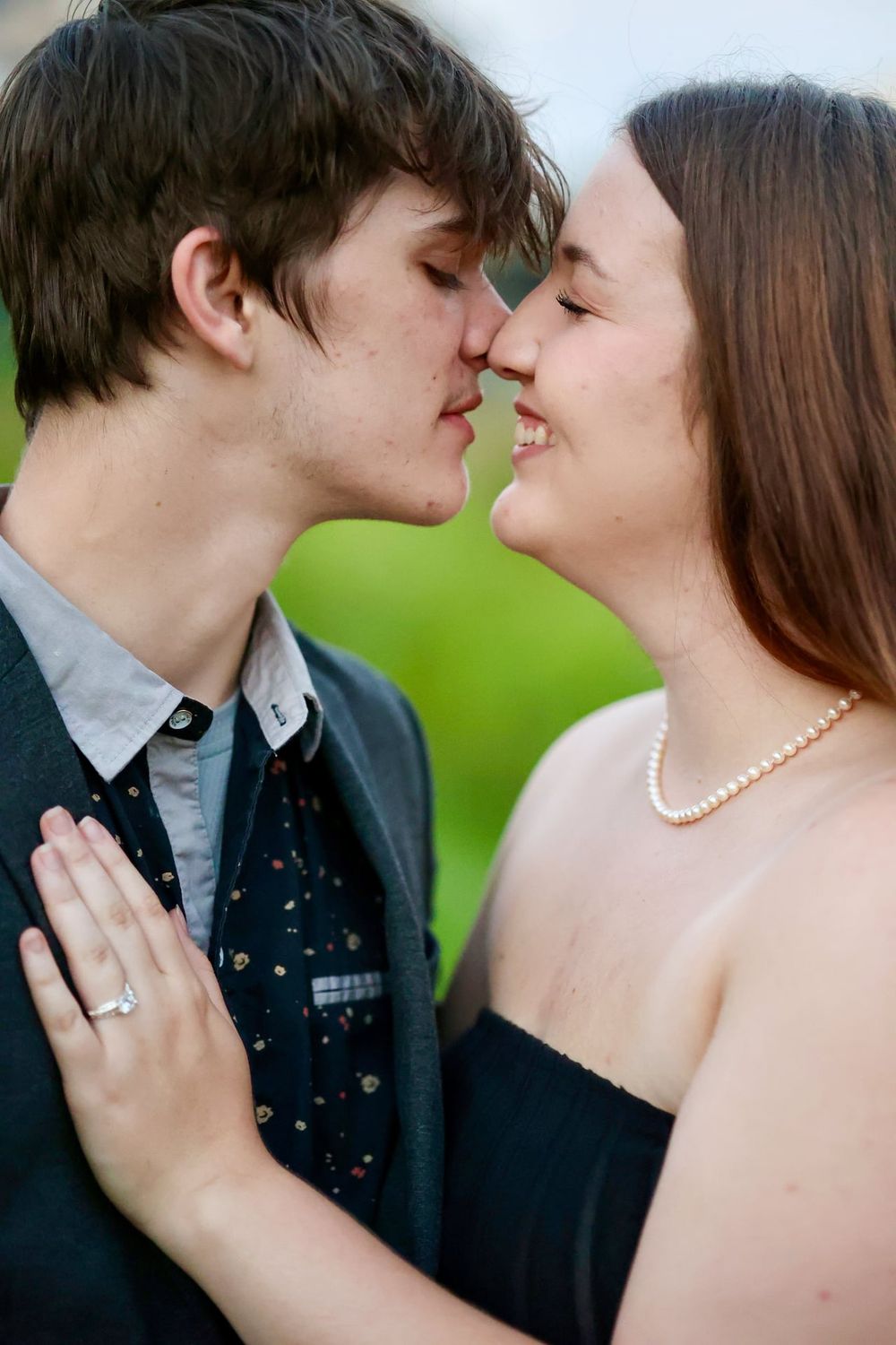 Romantic couple sharing an intimate moment in formal attire against a green background.