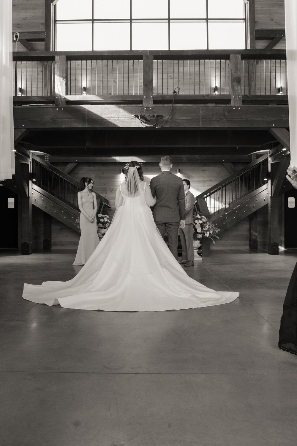 Long wedding dress train flows elegantly down stairs in black and white photography.