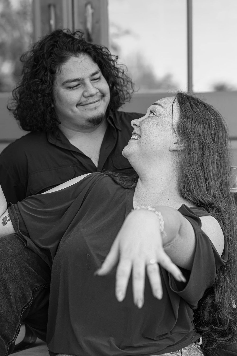 A happy couple sharing a joyful moment together in black and white.