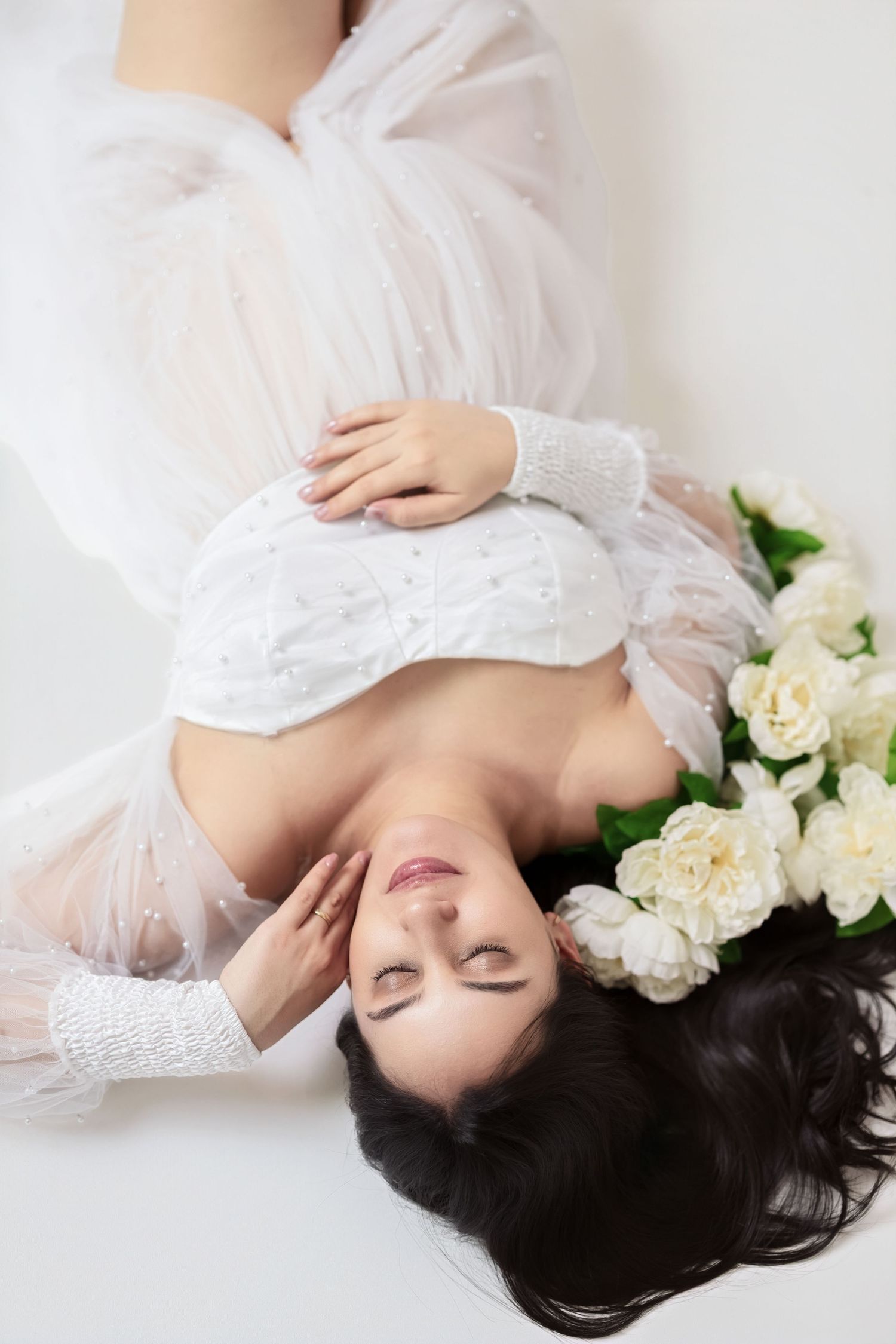 Ethereal portrait in white lace with delicate cream roses creating a dreamy romantic atmosphere.