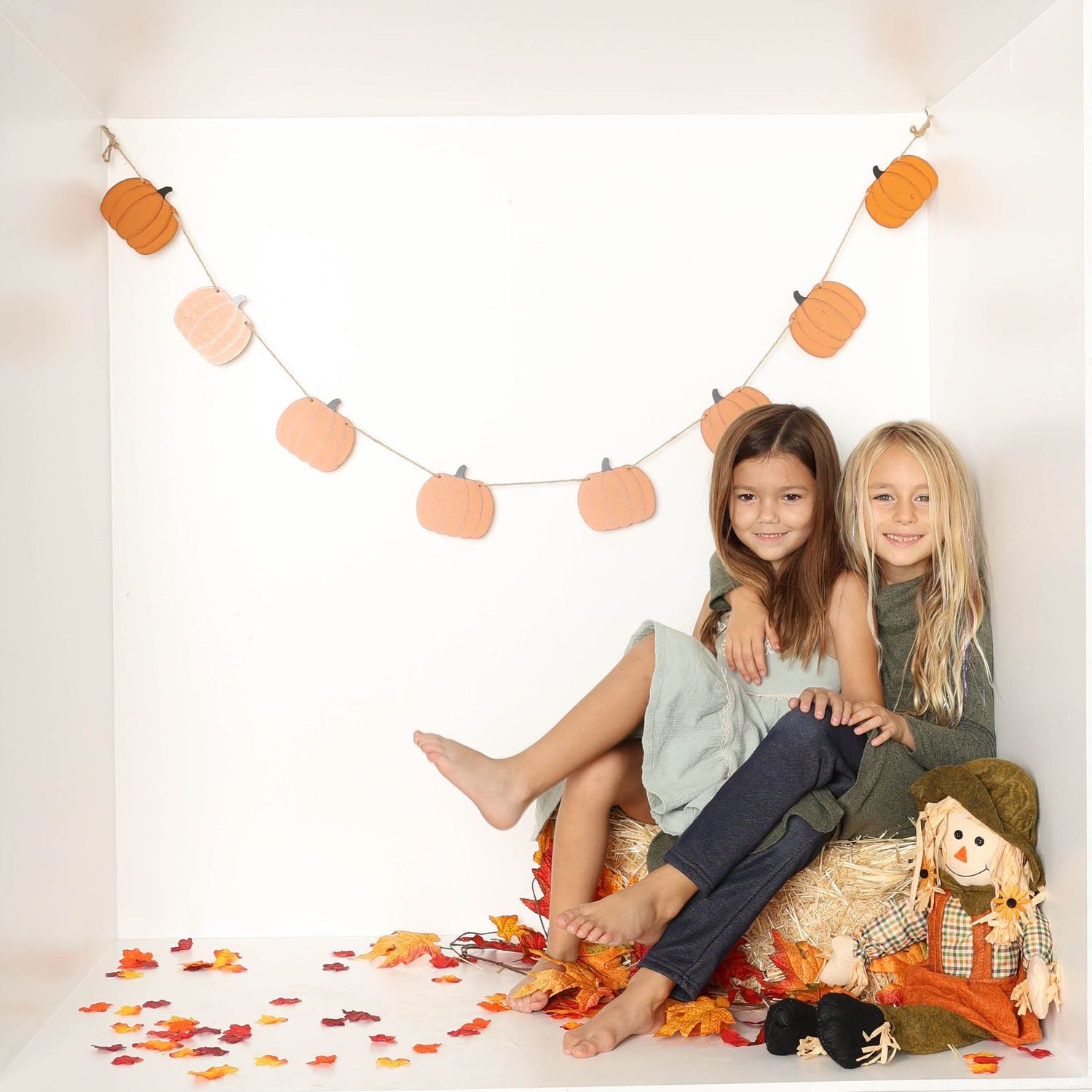 Fall themed photo setup with orange garland and autumn leaves on white background. Box photography session