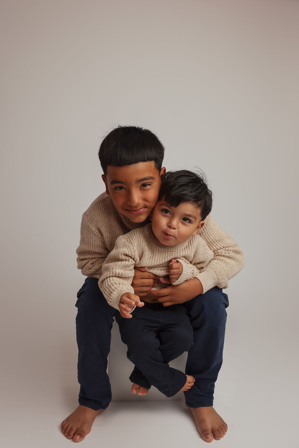 A series of playful expressions and poses against a neutral background showing someone crouching and making faces.