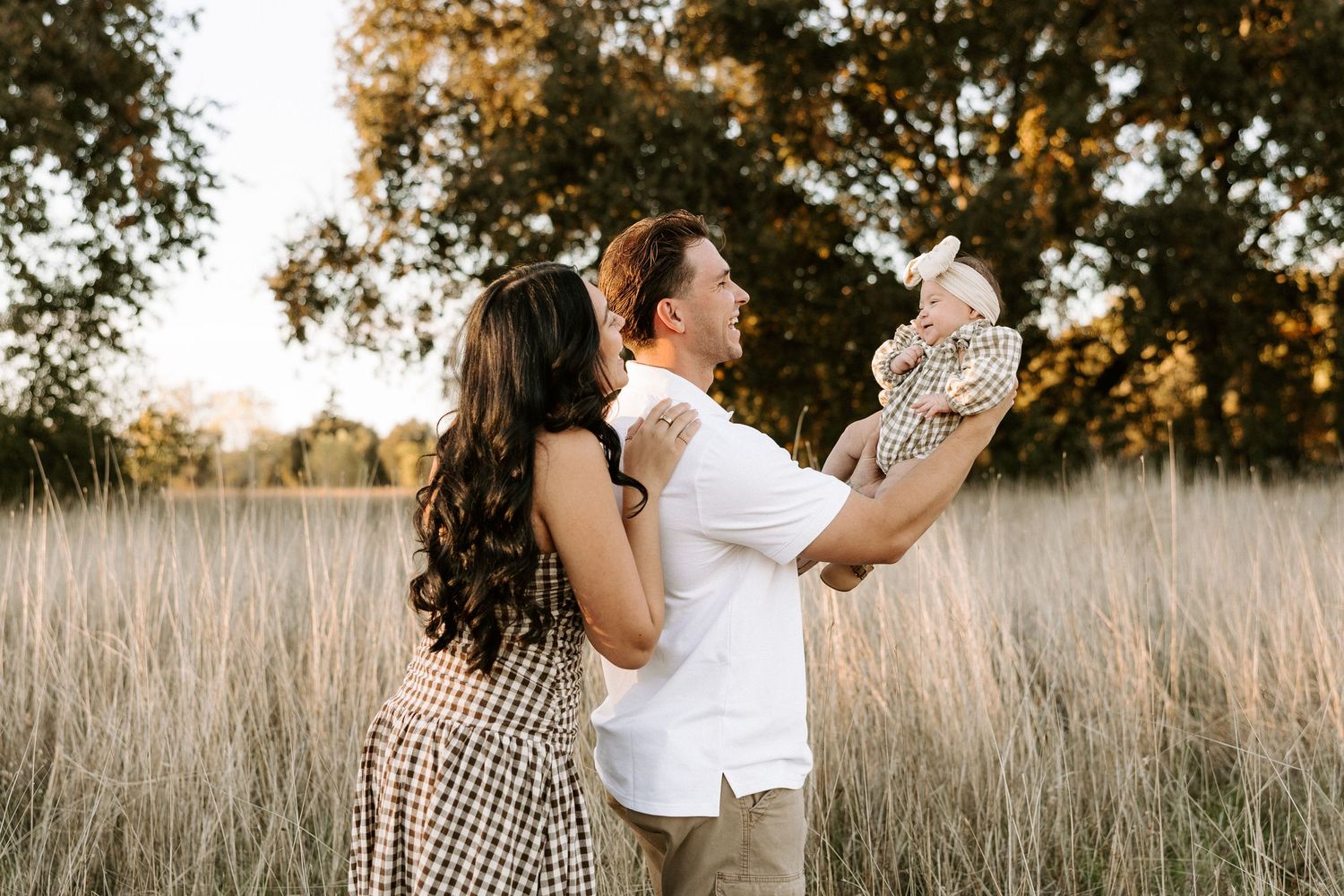 Couple shares tender moments together in a golden field of tall grass during sunset.