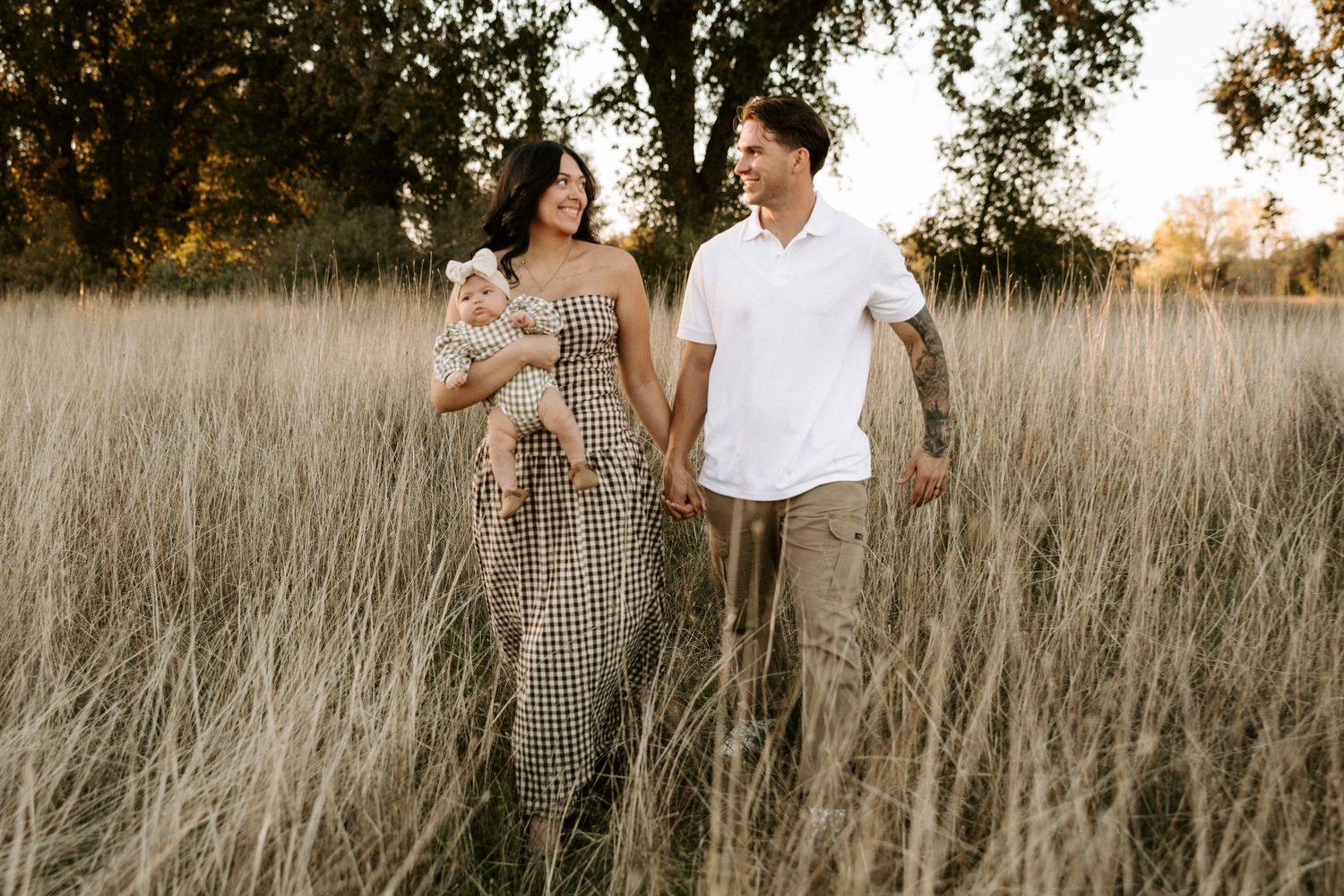 Romantic couple embraces while standing in a rustic field with warm autumn lighting.
