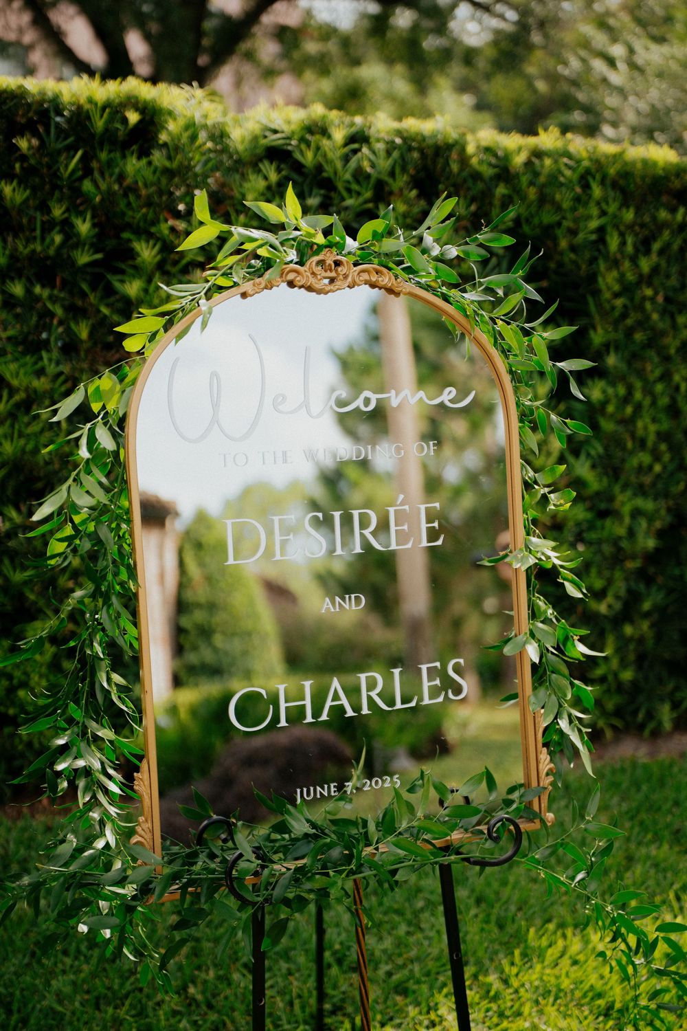 Elegant wedding welcome sign with greenery and names displayed on a mirror in at Casa Feliz in Winter Park Florida