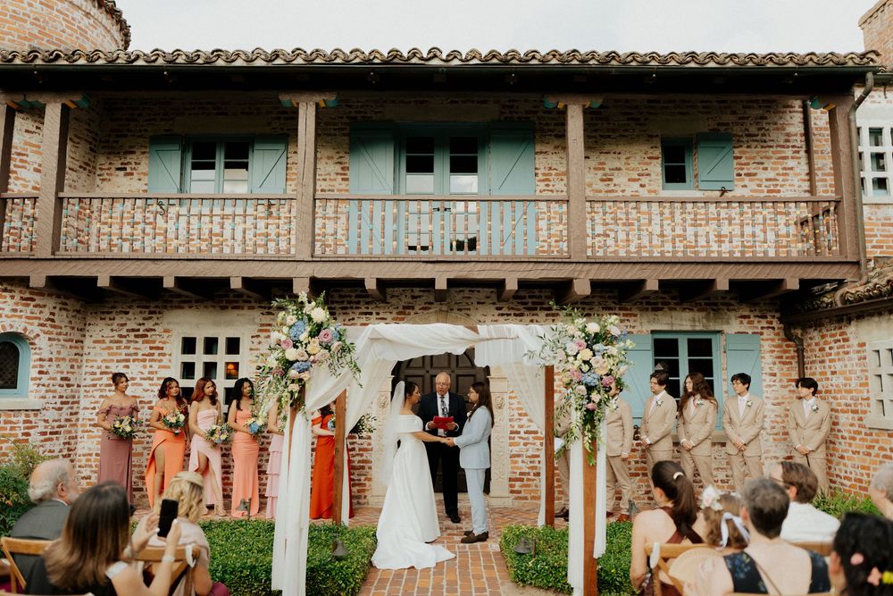 A rustic brick building with string lights and greenery creates a charming wedding reception atmosphere.