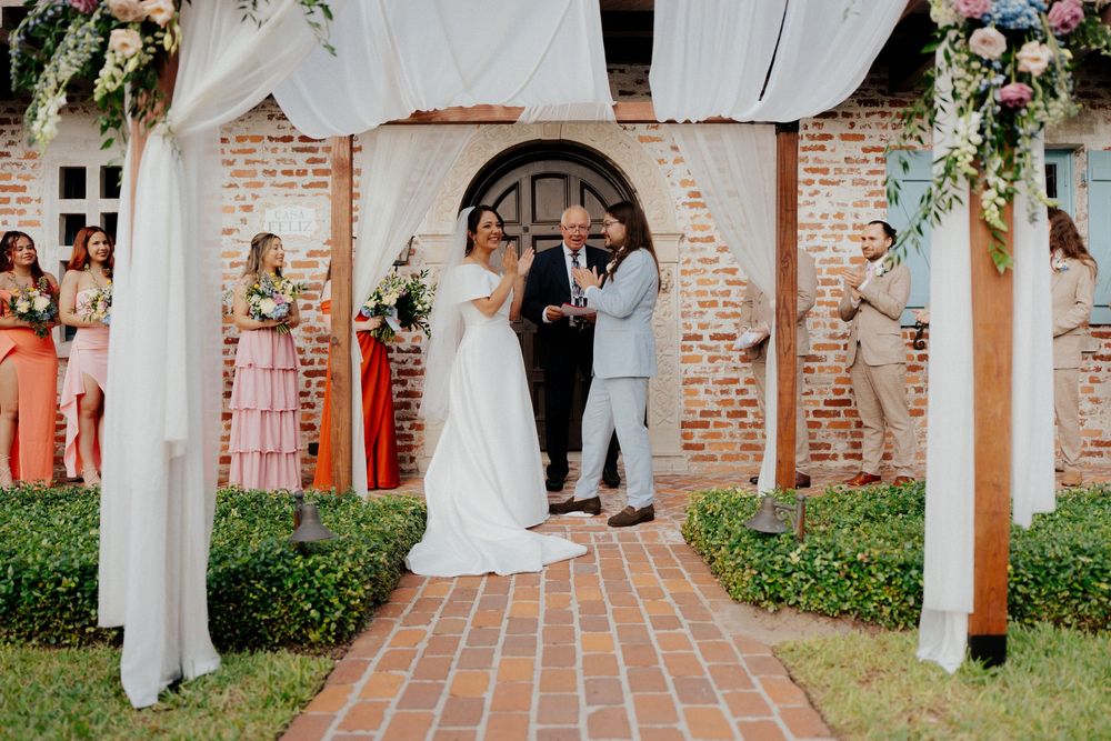 White fabric drapes between columns create an elegant outdoor wedding ceremony aisle.