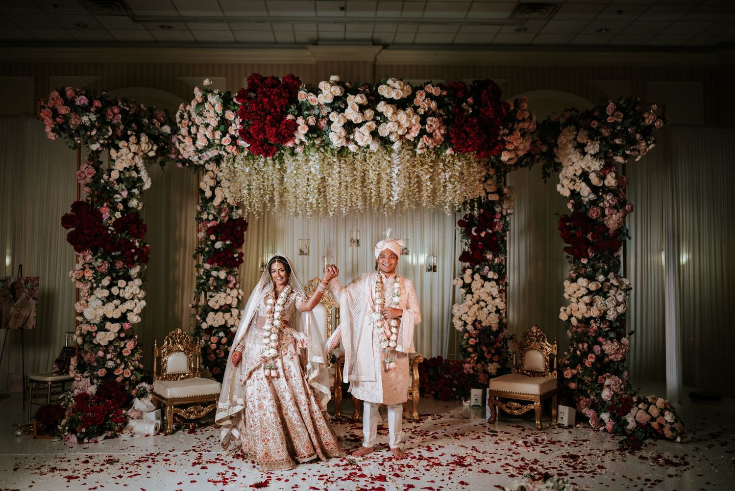 A romantic Indian wedding ceremony with floral decor and traditional attire in an elegant indoor setting.
