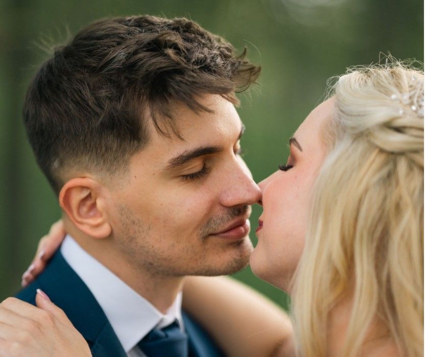 Egy romantikus esküvői pár közeli felvételek sorozatában osztja meg intim pillanatait egy zöld kültéri háttér előtt.