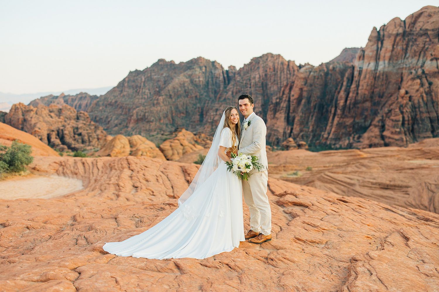 Romantic desert wedding photography with towering sandstone cliffs creating dramatic backdrop.