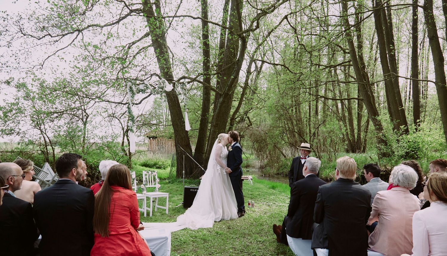 Wedding guests seated outdoors in a spring garden surrounded by blooming cherry blossom trees during a ceremony.