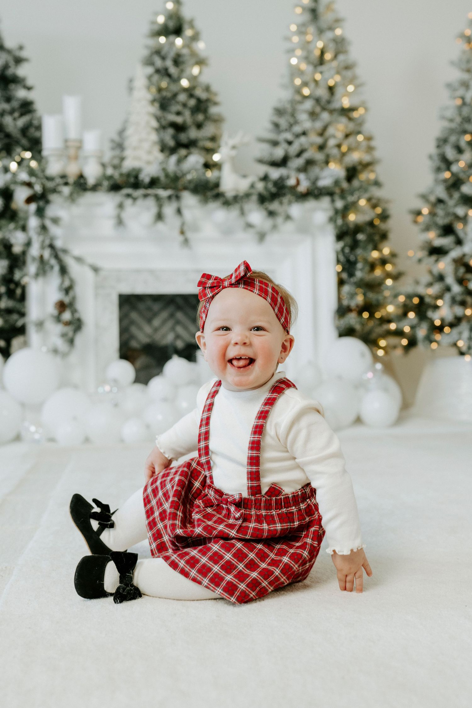 A festive holiday photo session with decorated Christmas trees and faux snow creating a magical winter wonderland scene.