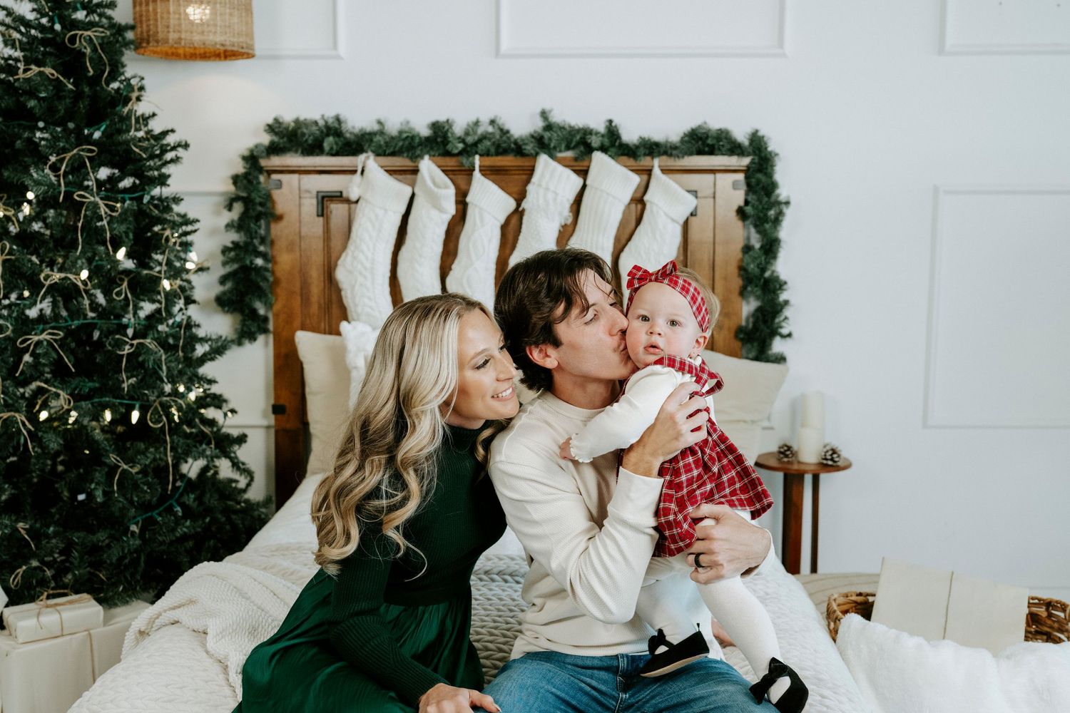 A festive Christmas scene with people sitting by a decorated tree in a cozy white room.