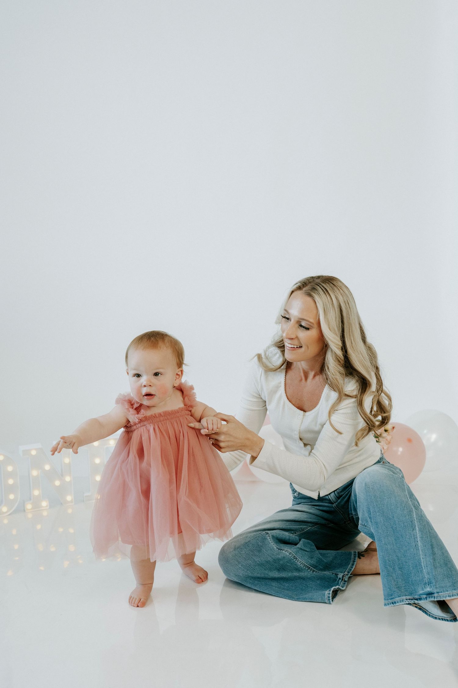 A sweet family moment captured in a series of playful poses against a white backdrop with twinkling lights.