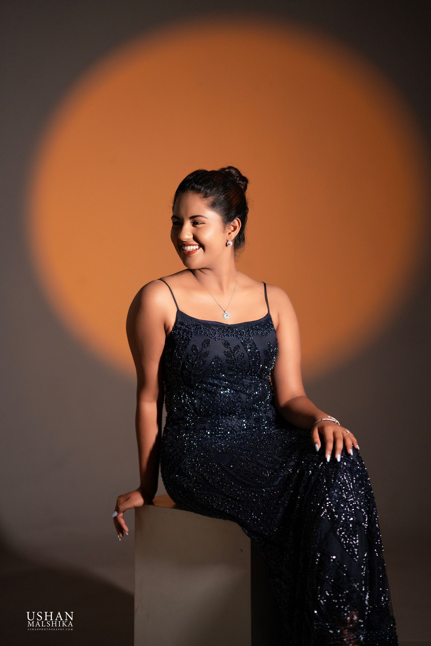 A sequence of silhouetted poses in a sparkly black evening gown against an orange and dark gradient background.