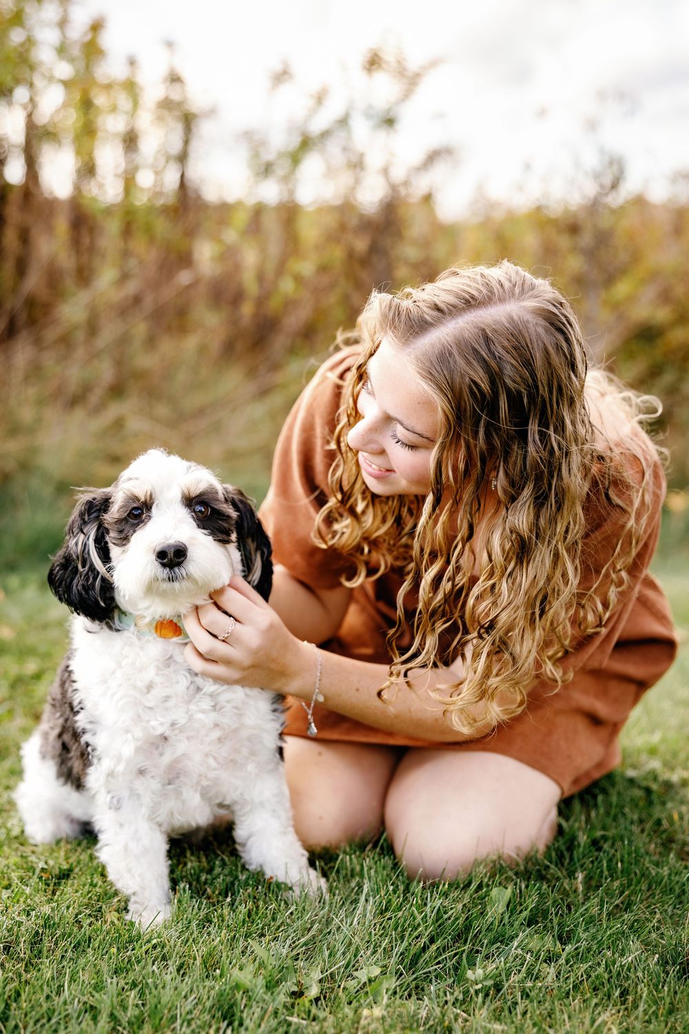 Sweet interaction between person and small black and white dog on grassy field.