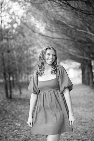 Portrait series in grey dress against moody autumn forest backdrop with falling leaves.