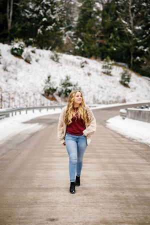 Winter photography session on snowy road with person in burgundy top and beige cardigan.